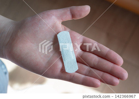 Young woman with medical adhesive plaster on the hand after vaccination. Fabric white bandage like first help for wound on the damage skin. Young woman with medical adhesive plaster on the hand after vaccination. Fabric white bandage like first help for wound on the damage skin. 142366967