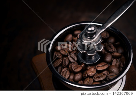 close-up photo of coffee beans in manual grinder machine in dark background close-up photo of coffee beans in manual grinder machine in dark background 142367069