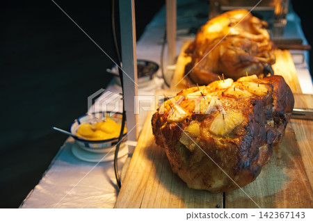 roasted ham pork with juicy pices pinapple slice in party dinner with hot lamp in dark background roasted ham pork with juicy pices pinapple slice in party dinner with hot lamp in dark background 142367143