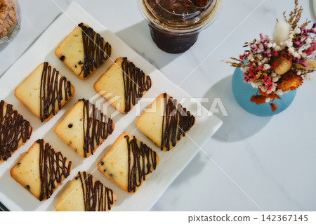many square muffins with chocolate sauce on white plate served with ice coffee many square muffins with chocolate sauce on white plate served with ice coffee 142367145