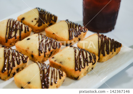 many square muffins with chocolate sauce on white plate served with ice coffee 142367146