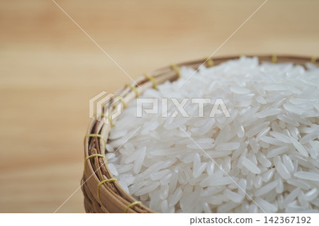 raw Thai's jasmine rice in Thai's traditional style bamboo's bowl on wooden dinner table raw Thai's jasmine rice in Thai's traditional style bamboo's bowl on wooden dinner table 142367192