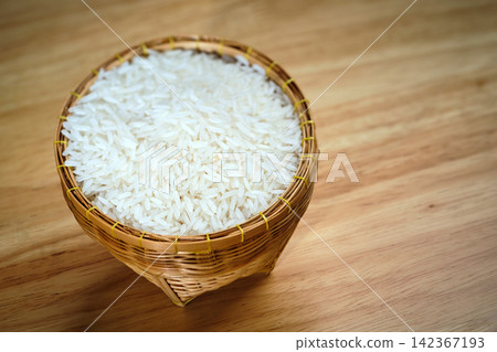 raw Thai's jasmine rice in Thai's traditional style bamboo's bowl on wooden dinner table raw Thai's jasmine rice in Thai's traditional style bamboo's bowl on wooden dinner table 142367193