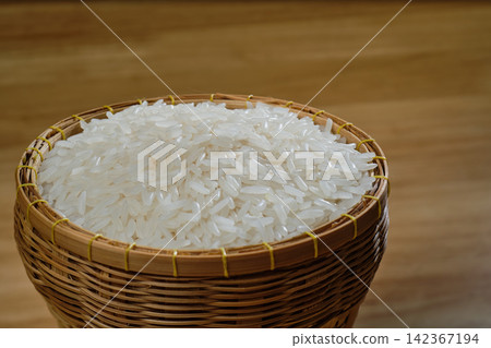 raw Thai's jasmine rice in Thai's traditional style bamboo's bowl on wooden dinner table raw Thai's jasmine rice in Thai's traditional style bamboo's bowl on wooden dinner table 142367194