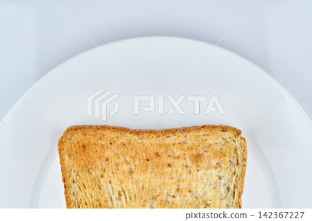 a part of golden crunchy toasted sliced whole wheat sandwich bread isolated on white dish and white background a part of golden crunchy toasted sliced whole wheat sandwich bread isolated on white dish and white background 142367227