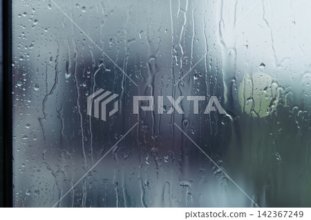 rain drops during raining in rainy day outside window glass with blurred background with water droplet flow down the surface rain drops during raining in rainy day outside window glass with blurred background with water droplet flow down the surface 142367249