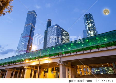 Moscow Central Circle (Little Ring, MCC, or MK MZD) and skyscrapers of the International Business Center (City) at night, with the super moon, Russia. Delovoy Tsentr railway station Moscow Central Circle (Little Ring, MCC, or MK MZD) and skyscrapers of the International Business Center (City) at night, with the super moon, Russia. Delovoy Tsentr railway station 142367395