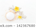 Soft powder spills from open container beside mirror. Yellow flowers add bright tropical flair. White coral fragment accents the clean minimalist scene. Ideal for beauty, skincare 142367680