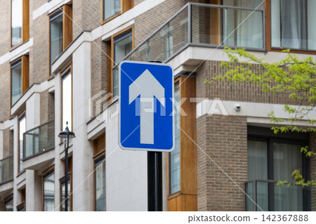 One way road sign in front of modern apartment building One way road sign in front of modern apartment building 142367888