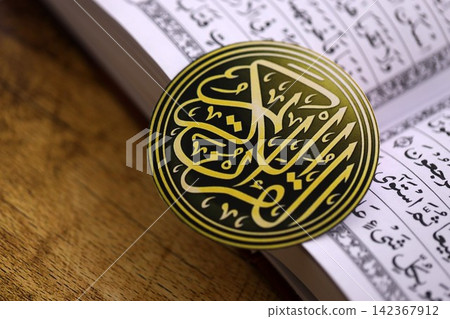 Sign with Al Quran inscription on Muslim holy book in mosque. Details of arabic calligraphy Sign with Al Quran inscription on Muslim holy book in mosque. Details of arabic calligraphy 142367912