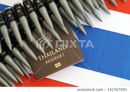 Thai passport and rifle bullets on flag. The concept of warfare and gun selling Thai passport and rifle bullets on flag. The concept of warfare and gun selling 142367993
