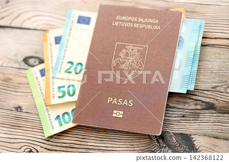 Lithuania passport lies with euro money banknotes on wooden table. Cash and payments in Europe Lithuania passport lies with euro money banknotes on wooden table. Cash and payments in Europe 142368122