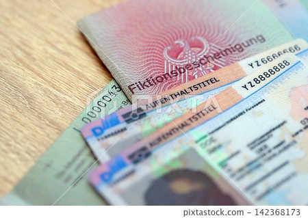 German Permanent resident card and document specimen lies on wooden table. Aufenthaltstitel German Permanent resident card and document specimen lies on wooden table. Aufenthaltstitel 142368173
