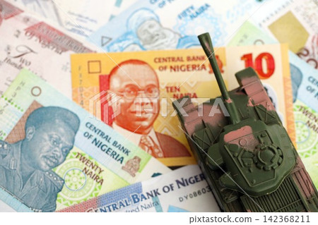 Nigerian naira currency money bills and toy tank. The concept of army funds and weapons sales Nigerian naira currency money bills and toy tank. The concept of army funds and weapons sales 142368211