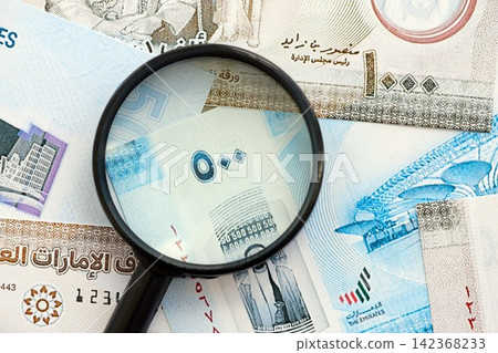 United Arab Emirates dirham currency money bills and magnifying glass. The concept of financial monitoring and taxation United Arab Emirates dirham currency money bills and magnifying glass. The concept of financial monitoring and taxation 142368233