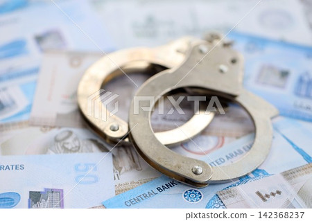 United Arab Emirates dirham currency money bills and handcuffs. The concept of criminal United Arab Emirates dirham currency money bills and handcuffs. The concept of criminal 142368237