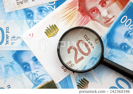 Israel New Shekels banknotes and magnifying glass. The current Israel money bills with loupe 142368396