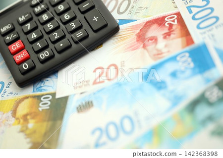 Israel New Shekels banknotes and calculator. The current Israel money bills and calc lies on table Israel New Shekels banknotes and calculator. The current Israel money bills and calc lies on table 142368398