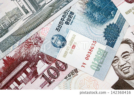 North Korean won money bills in big amount lies on white color table close up North Korean won money bills in big amount lies on white color table close up 142368416
