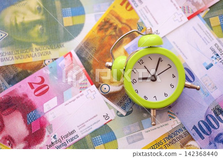 Swiss franc banknotes and alarm clock. The current francs money bills and clock lies on table Swiss franc banknotes and alarm clock. The current francs money bills and clock lies on table 142368440