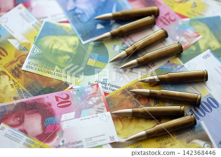 Swiss franc banknotes and bullets. The current francs money bills and ammo lies on table Swiss franc banknotes and bullets. The current francs money bills and ammo lies on table 142368446