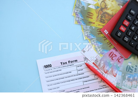 Swiss franc banknotes and tax form with pen on blue. The current francs money bills lies on tax form Swiss franc banknotes and tax form with pen on blue. The current francs money bills lies on tax form 142368461