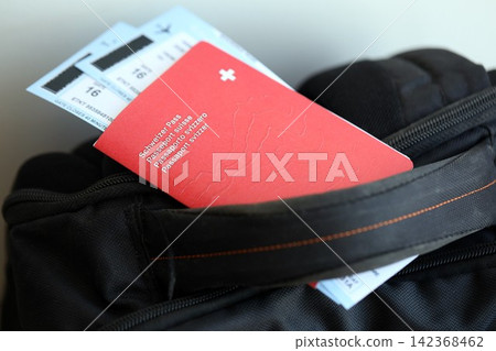 Swiss passport and avia tickets on travel bag. Pass and boarding tokens on bag close up Swiss passport and avia tickets on travel bag. Pass and boarding tokens on bag close up 142368462