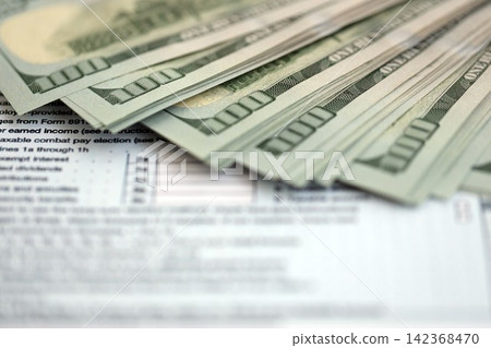 Big amount of United States hundred dollar bills in bunch on table with tax return form 142368470
