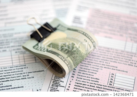 Big amount of United States hundred dollar bills on table with tax return form close up Big amount of United States hundred dollar bills on table with tax return form close up 142368471