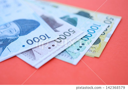 South Korean won money bills in big amount lies on red color table close up South Korean won money bills in big amount lies on red color table close up 142368579