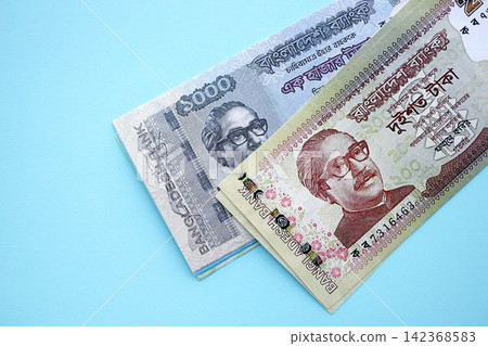 Bangladeshi taka money bills in big amount lies on teal color table close up Bangladeshi taka money bills in big amount lies on teal color table close up 142368583