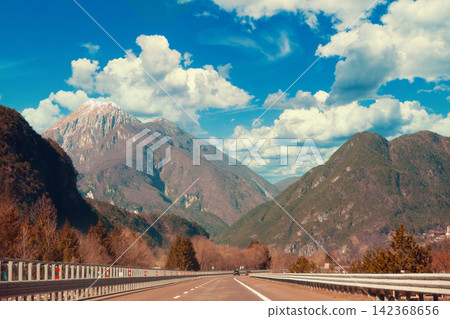 View of beautiful mountain landscape through the windscreen on a sunny day. Driving a car on mountain winding road in National park Picos de Europa. Cantabria, Spain, Europe View of beautiful mountain landscape through the windscreen on a sunny day. Driving a car on mountain winding road in National park Picos de Europa. Cantabria, Spain, Europe 142368656