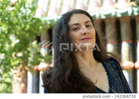 Beautiful adult Armenian woman looking directly at camera with gentle smile outdoors in sunlight Beautiful adult Armenian woman looking directly at camera with gentle smile outdoors in sunlight 142368738