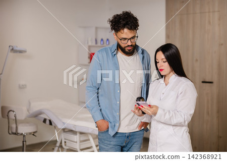Doctor consulting patient using a smartphone in clinic Doctor consulting patient using a smartphone in clinic 142368921