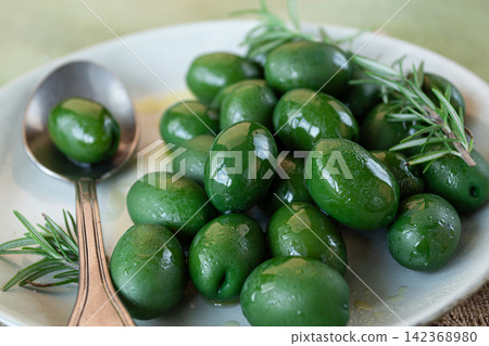 Chalkidiki olives, classic Greek green olive, on a plate, with a spoon, top view, no people, Chalkidiki olives, classic Greek green olive, on a plate, with a spoon, top view, no people, 142368980