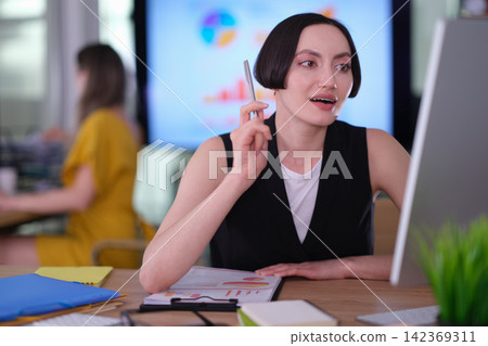 Businesswoman reads detailed information on computer screen Businesswoman reads detailed information on computer screen 142369311