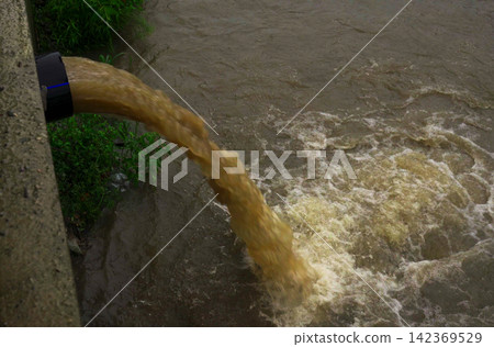 Polluted water runoff flows into a river, harming local ecosystems Polluted water runoff flows into a river, harming local ecosystems 142369529