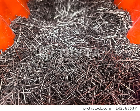 Metallic nails scattered in a vibrant container create an artful display Metallic nails scattered in a vibrant container create an artful display 142369537
