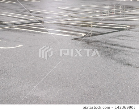 被雨水浸透的瀝青停車場 / 雨天的城市背景圖片,有水坑和白色線條。 被雨水浸透的瀝青停車場 / 雨天的城市背景圖片,有水坑和白色線條。 142369905