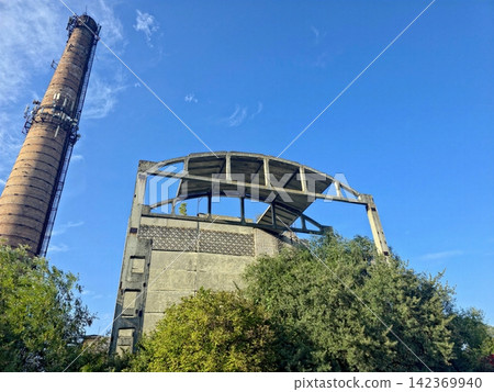 Ruins of an Old Industrial Site With Brick Chimney and Lush Greenery Ruins of an Old Industrial Site With Brick Chimney and Lush Greenery 142369940
