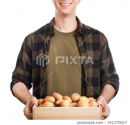 Smiling farmer holding a wooden crate with fresh organic potato harvest. Local agriculture and sustainable vegetable farming concept Smiling farmer holding a wooden crate with fresh organic potato harvest. Local agriculture and sustainable vegetable farming concept 142370027