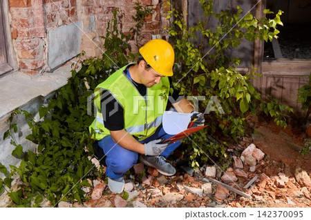 Construction inspector reviewing plans amid rubble at night Construction inspector reviewing plans amid rubble at night 142370095