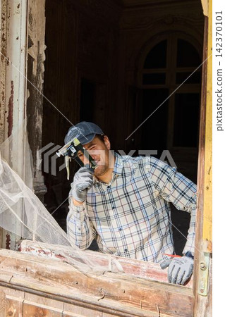 Restoration specialist assessing wood window sash during day Restoration specialist assessing wood window sash during day 142370101
