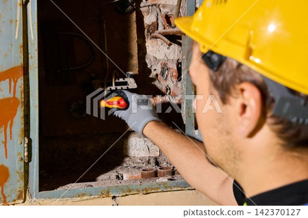 Electrician conducts live circuit testing with specialized tools Electrician conducts live circuit testing with specialized tools 142370127