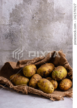 Raw uncooked potato on light background Raw uncooked potato on light background 142370327