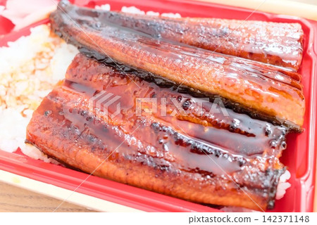 A takeout bento box featuring perfectly grilled eel served over white rice. A takeout bento box featuring perfectly grilled eel served over white rice. 142371148