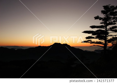 從愛媛縣石槌山脈的龜森山上,可以看到日落後神奇時刻,雲海和雄偉的石槌山輪廓的壯麗景色。 從愛媛縣石槌山脈的龜森山上,可以看到日落後神奇時刻,雲海和雄偉的石槌山輪廓的壯麗景色。 142371377