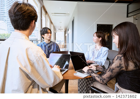 年輕的商務人士在共享辦公空間使用筆記型電腦開會。 年輕的商務人士在共享辦公空間使用筆記型電腦開會。 142371602