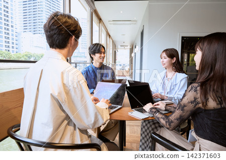 Four young business people are having a meeting using their laptops in a cafe. Four young business people are having a meeting using their laptops in a cafe. 142371603