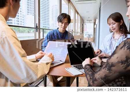 一位年輕的商務人士在咖啡館裡用筆記型電腦開會。 142371611